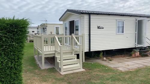a small white house with a porch and a staircase at Skegness,North shore holiday park , new 8 berth caravan for rent in Skegness