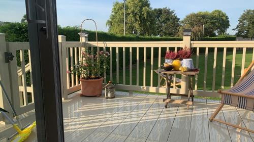 a porch with a fence and a table with flowers at Skegness,North shore holiday park , new 8 berth caravan for rent in Skegness