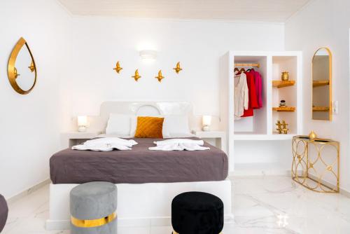a white bedroom with a bed and two stools at GK Santorini home art in Perivolos