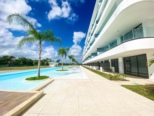 a swimming pool next to a building with palm trees at Xeliter Cana Rock Punta Cana in Punta Cana