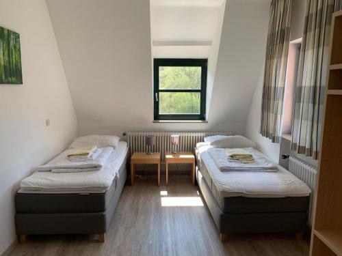 アルトドルフ・バイ・ニュルンベルクにあるCampus Prackenfelsのベッド2台、テーブル、窓が備わる客室です。