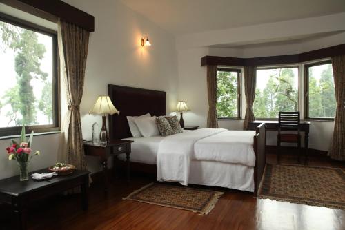 a bedroom with a large white bed and windows at Sourenee Tea Estate in Mirik