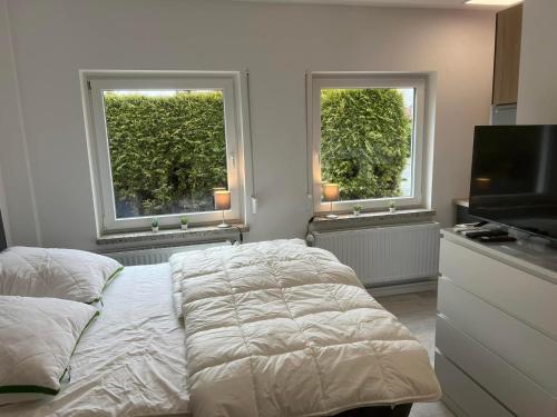 a bedroom with a bed and a television and two windows at Mimi's Ostseeglück in Grömitz