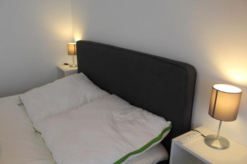 a bed with a black headboard and two tables with lamps at Mimi's Ostseeglück in Grömitz