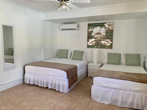 two beds in a room with white walls and a ceiling at Tu Casita en Aruba in Palm-Eagle Beach