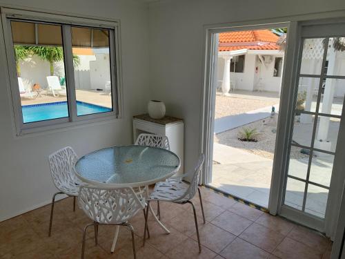 a dining room with a glass table and chairs at Tu Casita en Aruba in Palm-Eagle Beach