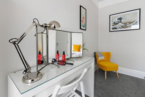 a desk with a lamp and a yellow chair at Admirals Place - Contemporary Townhouse With Spacious and Flexible Accommodation in Torquay