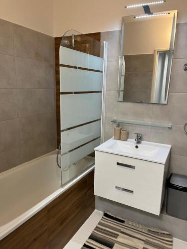 een badkamer met een wastafel, een bad en een spiegel bij Kawalerka SŁONECZNA osiedle DOBRZEC in Kalisz