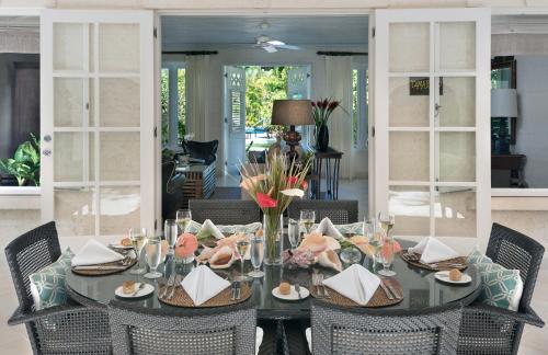 uma sala de jantar com uma mesa com cadeiras e uma mesa; em Coral Reef Club em Saint James