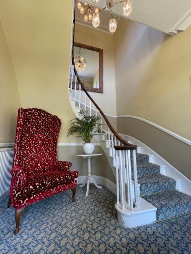 a stairway with a red chair and a stair case at Park Farm Hotel in Norwich