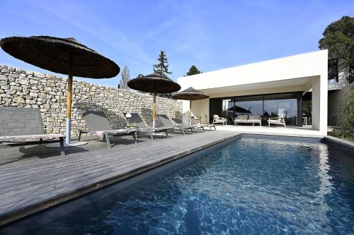 a house with a swimming pool with umbrellas at Les Loges en Provence - Villa Contemporelle in Pujaut