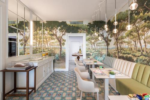 a restaurant with tables and chairs and a wall mural at Palazzo Marziale in Sorrento