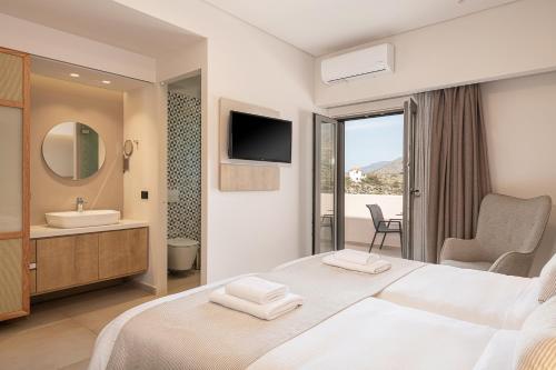 a bedroom with a bed and a sink and a mirror at Elafonisi Resort by Kalomirakis Family in Elafonisi