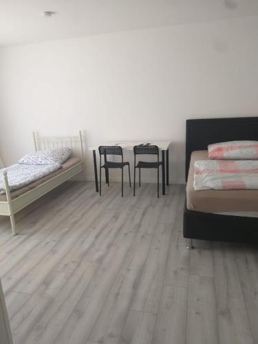 two beds and two chairs in a room with wooden floors at Pension Rückert in Kassel