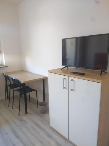 a flat screen tv on top of a cabinet with a table at Pension Rückert in Kassel