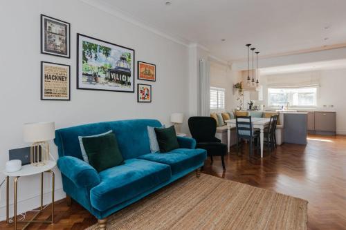 a living room with a blue couch and a dining room at Newly Refurbished 4 Bedroom House in East London in London