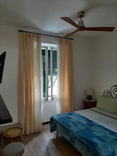 um quarto com uma cama, uma ventoinha de tecto e uma janela em Retro' BeB em La Spezia