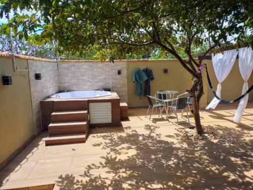 a patio with a tub and a table and a chair at CASA COM SPA DE HIDRO, AQUECEDOR E CROMOTERAPIA A 1,0 kM DO CENTRO in Chapada dos Guimarães