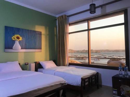 a bedroom with two beds and a large window at Villa Misk in Aswan