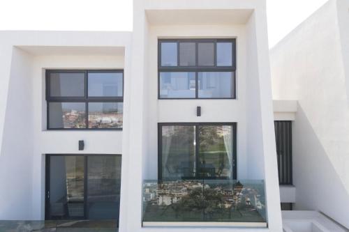 a facade of a white building with black windows at Sky Island House - Design Maisonette Kallithea in Kallithea Halkidikis