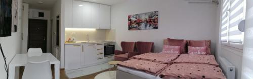 une chambre avec un lit rose et une cuisine dans l'établissement Spring deluxe, à Novi Sad