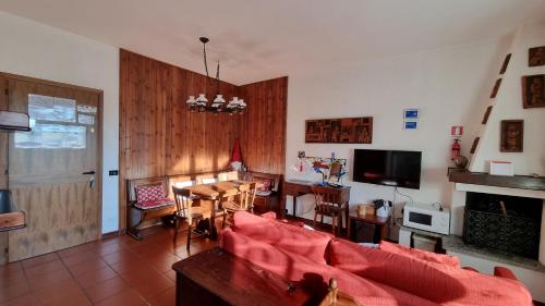 - un salon avec un canapé rouge et une télévision dans l'établissement Appartamento Isabella - Residence Montesole, à Ponte di Legno