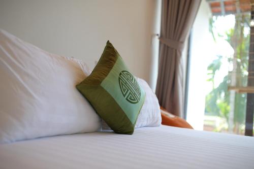a green pillow sitting on top of a bed at The Purple Hue Homestay in Hue