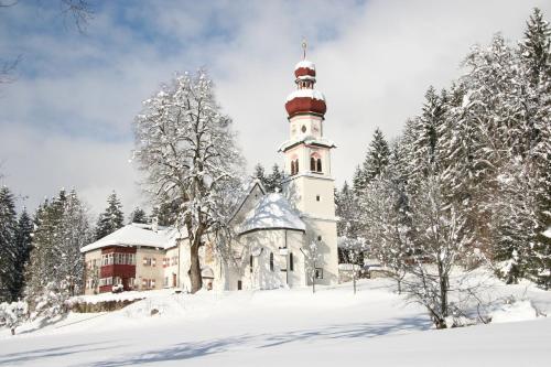 an old building with a tower in the snow at Alpenhotel Speckbacher Hof in Gnadenwald