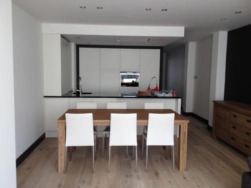 cocina y comedor con mesa de madera y sillas blancas en Apartment Mauritius, en Knokke-Heist