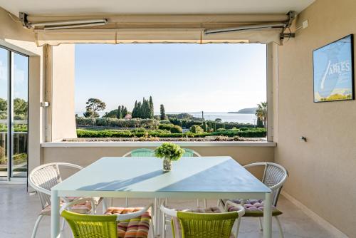 une table et des chaises dans une pièce avec une grande fenêtre dans l'établissement L'Anglet par Dodo-a-Cassis, à Cassis