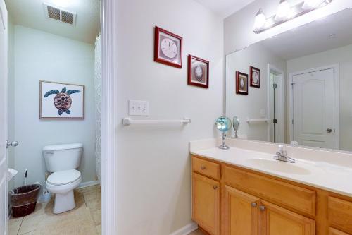 a bathroom with a sink and a toilet and a mirror at Seaside - Silver Lining 202B in Virginia Beach