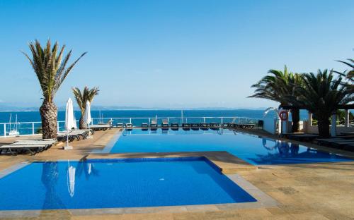 a swimming pool with a view of the ocean at Hotel Club Sunway Punta Prima in Es Pujols