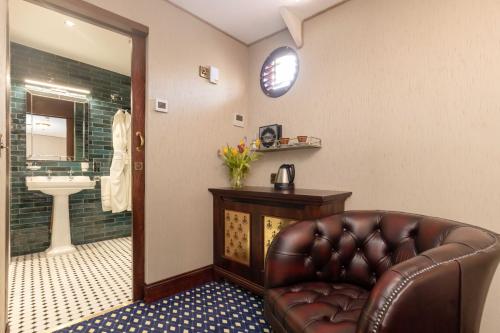 a leather couch in a bathroom with a sink at Ocean Mist Leith in Edinburgh