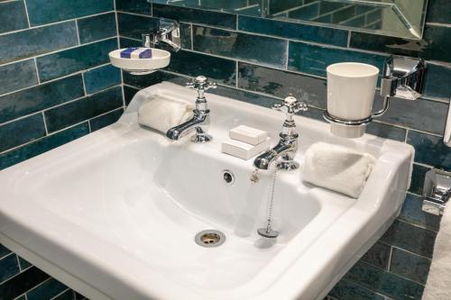 a white sink in a bathroom with blue tiles at Ocean Mist Leith in Edinburgh
