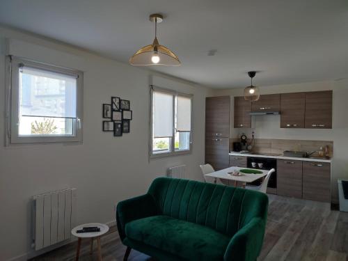 uma sala de estar com um sofá verde e uma cozinha em Calme et charmant T1 bis em Brest