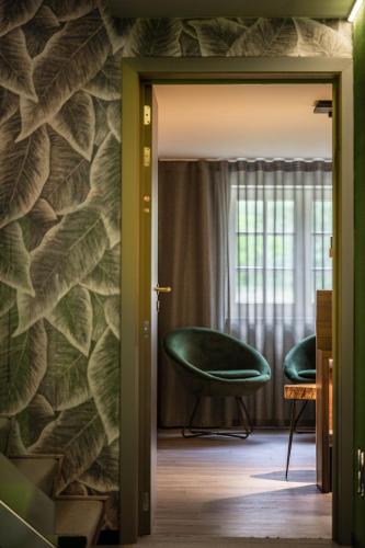a room with a green chair and a window at La Butte aux Bois a Small Luxury Hotel of the World in Lanaken