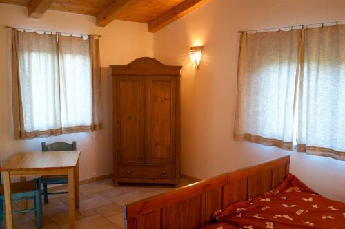 a bedroom with a bed and a table and windows at Casa Stazzutz in Luogosanto