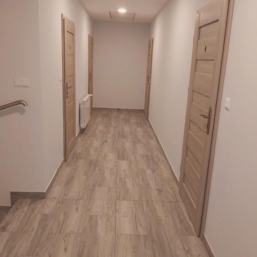 an empty hallway with two doors and wooden floors at Pokoje U lalusia in Muszyna