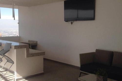 a living room with a couch and a tv on a wall at Nuevo y Lujoso departmento residencial Querétaro. in Querétaro