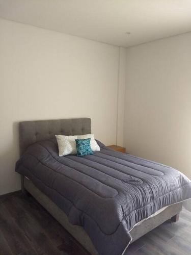 a bedroom with a large bed with blue pillows at Nuevo y Lujoso departmento residencial Querétaro. in Querétaro