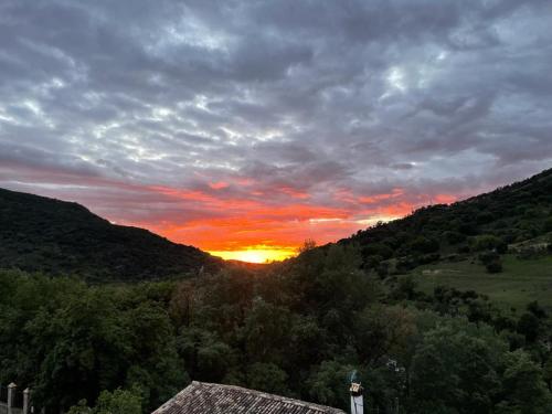 a sunset in the mountains with the sun setting at Suite Rural Oasis in Benamahoma