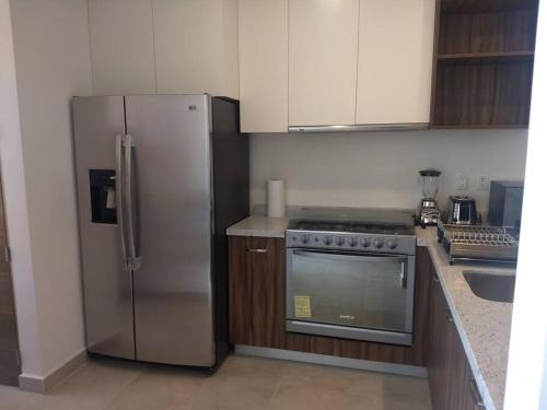 a kitchen with a stainless steel refrigerator and a stove at Nuevo y Lujoso departmento residencial Querétaro. in Querétaro