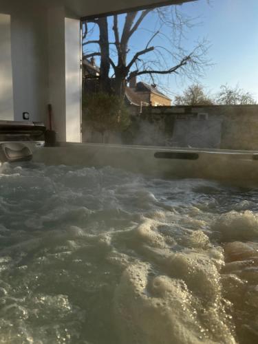a bathtub filled with water with steam coming out at La petite Brainoise - Gîte avec salle jacuzzi 120 jets in Braine