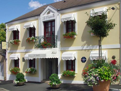 a building with potted plants on the side of it at HOTEL LA COGNETTE A 25 Kilomètres de Châteauroux et 30 Kilomètres de Bourges in Issoudun