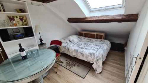 a small bedroom with a bed and a glass table at Appartement Cœur de Paris avec vue sur les toits in Paris