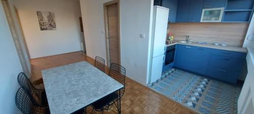 eine Küche mit blauen Schränken, einem Tisch und einem Kühlschrank in der Unterkunft Apartman Blok 45 (reka Sava) in Belgrad