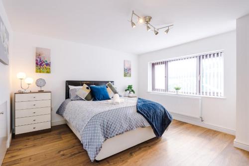a white bedroom with a bed and a window at Sunshine Cottage by Happy Sunshine Stay in Golborne