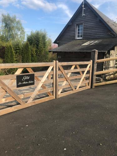 a wooden gate with a sign in front of a house at Gîte 'les matins calmes ' in Cheffreville-Tonnencourt