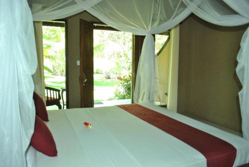 a bedroom with a white bed with a window at Pondok Rahayu Guest House in Pemuteran