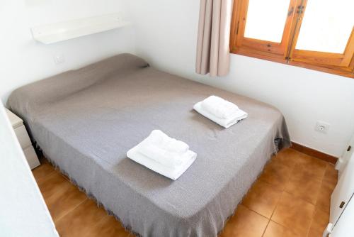 a bed in a room with two white towels on it at Apartamento Menorca Arenal d'en Castell in Arenal d'en Castell